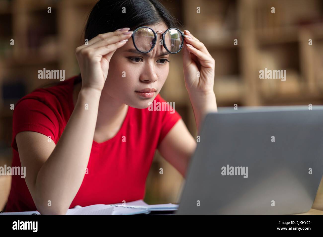 Konzentriert smart teen koreanisch weiblich Student nimmt aus Brille sehen online Lektion in Laptop Stockfoto