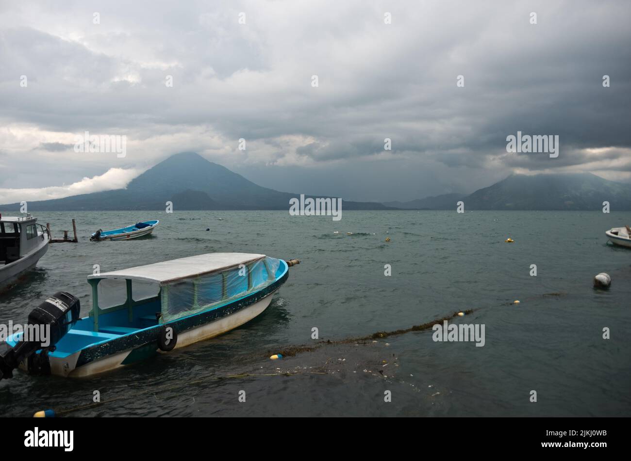 Lake Atitlan in Guatemala an einem regnerischen Tag im Juni. Alte Fischerboote schwimmen im Wasser. Stockfoto