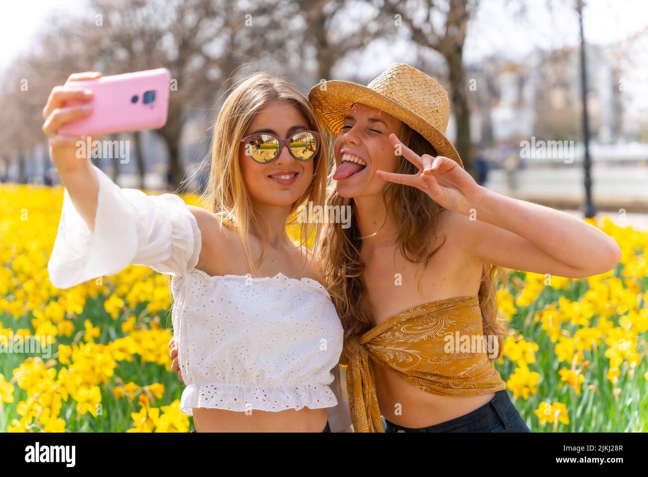 Freunde im Urlaub in der Stadt mit Strohhüten neben einigen schönen gelben Blumen, lächeln viel und genießen den Frühling ein Selfie Stockfoto