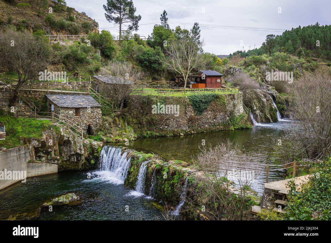 Eine malerische Aussicht auf den Wasserfall von Poco da Broca in Barriosa, umgeben von Bäumen und Häusern Stockfoto