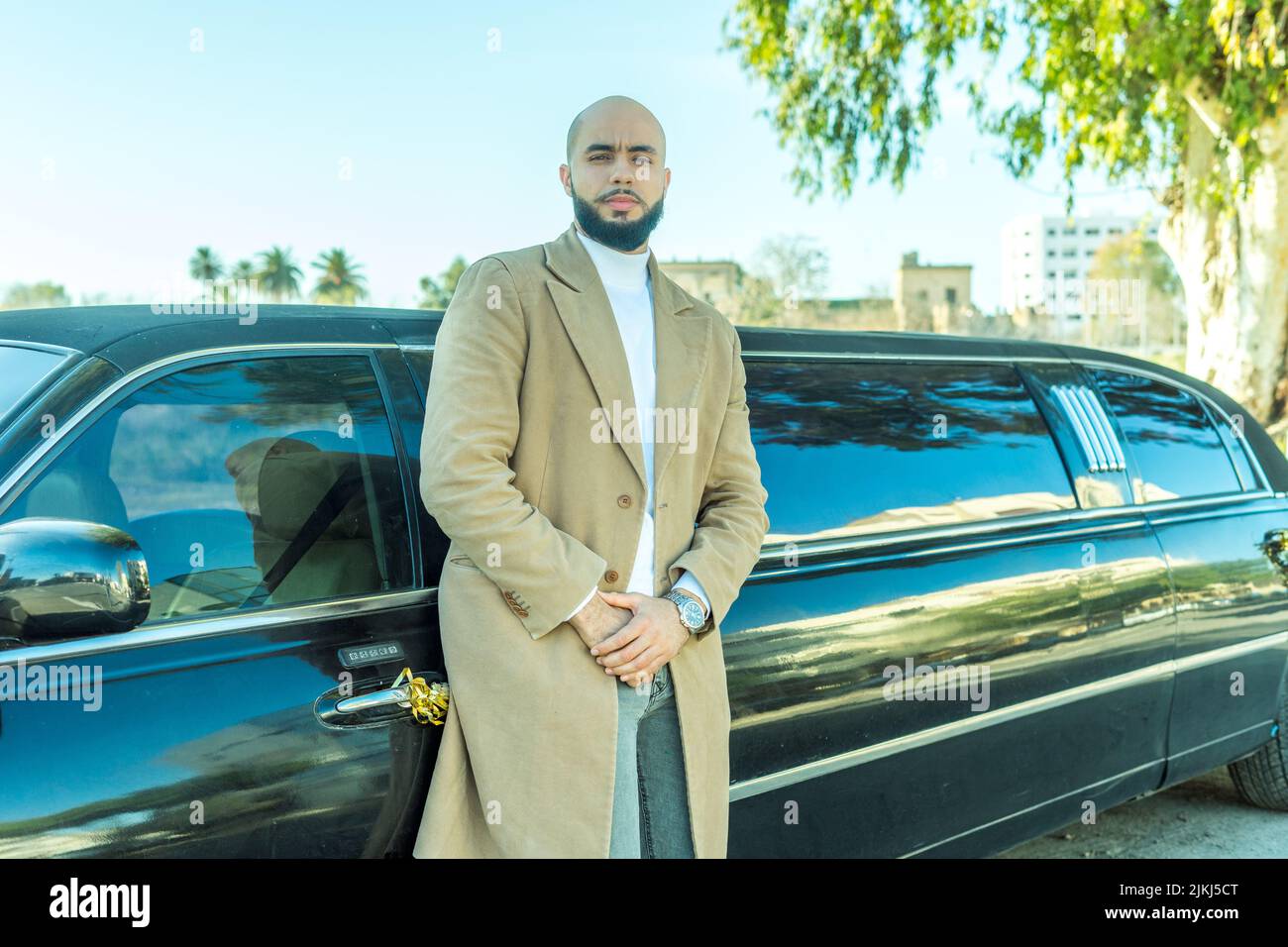 Attraktives kaukasisches Modell, das sich im Freien an einen Limousinenwagen lehnt Stockfoto