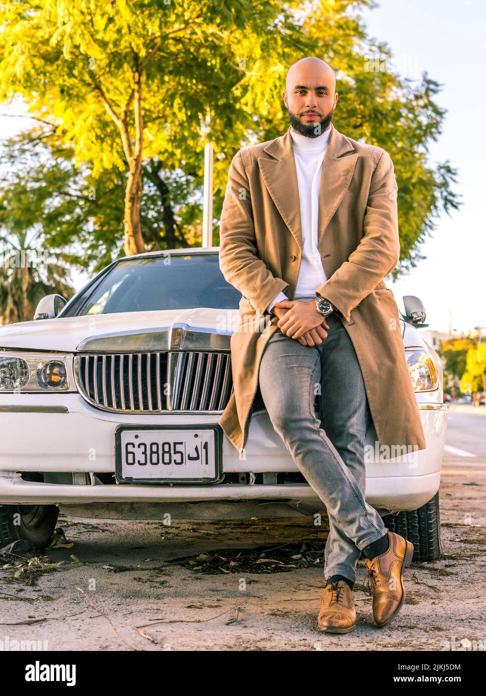 Attraktives kaukasisches Modell, das sich im Freien an einen Limousinenwagen lehnt Stockfoto