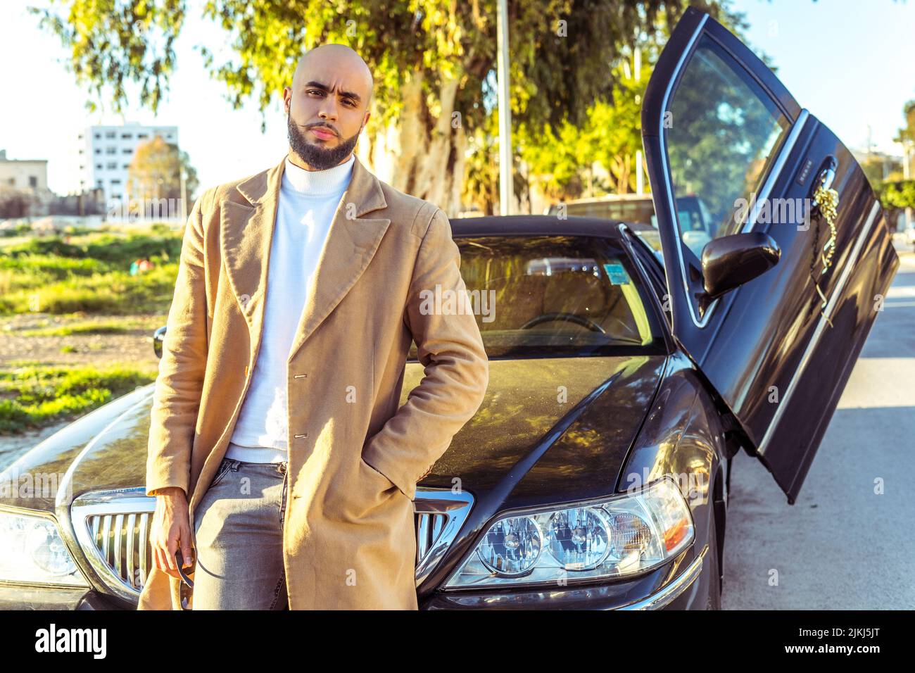 Attraktives kaukasisches Modell, das sich im Freien an einen Limousinenwagen lehnt Stockfoto