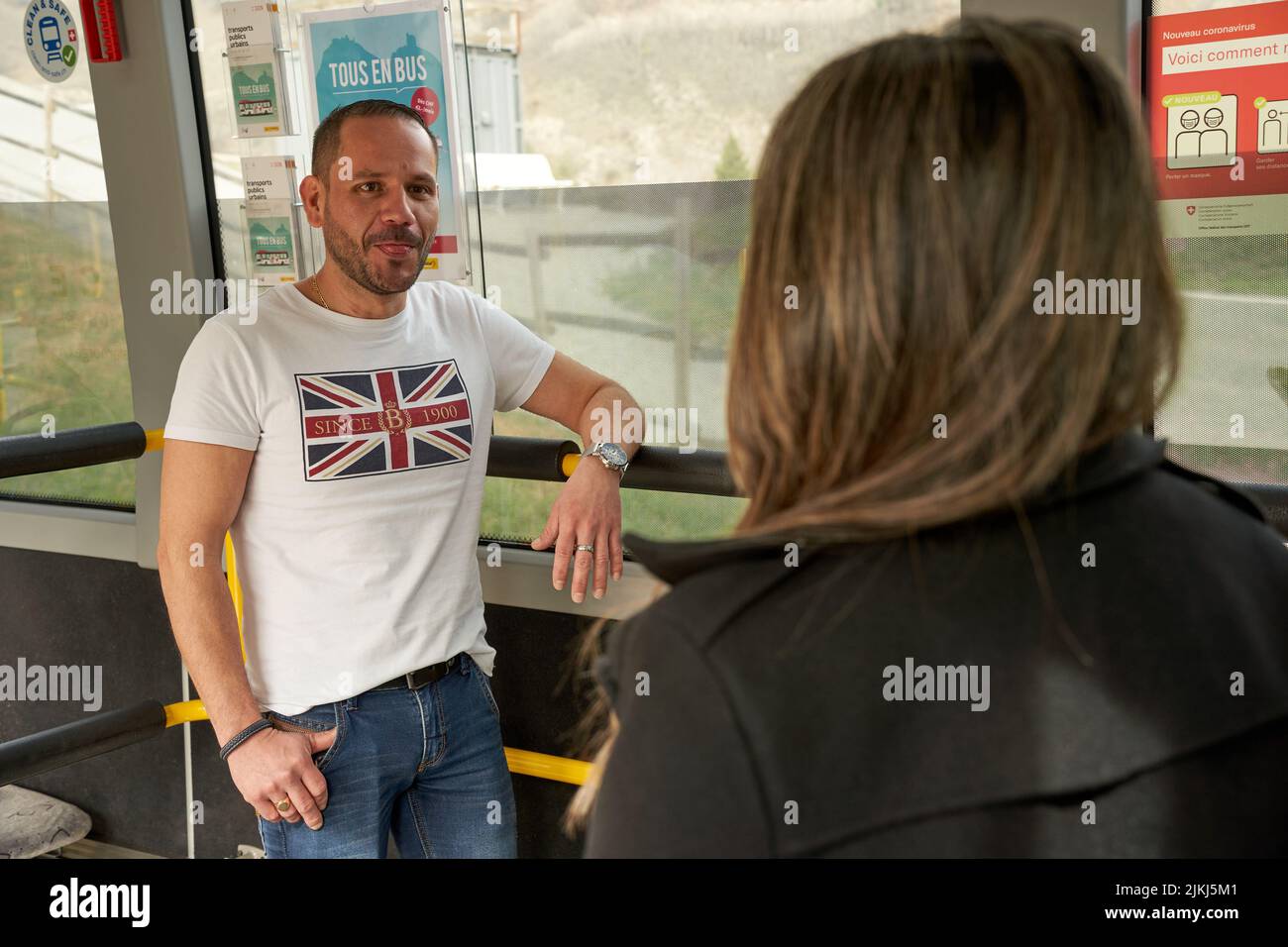 Zwei Fahrgäste stehen während der Fahrt in einem Bus und sprechen Stockfoto