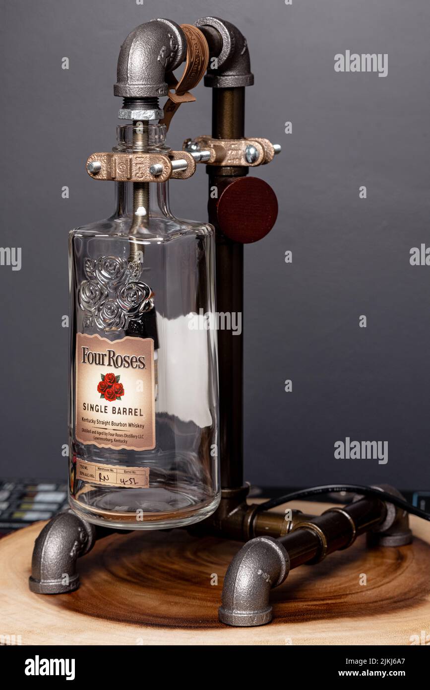 Eine vertikale Aufnahme von vier Rosen Steampunk Bourbon Flasche Pfeifenlampe Stockfoto