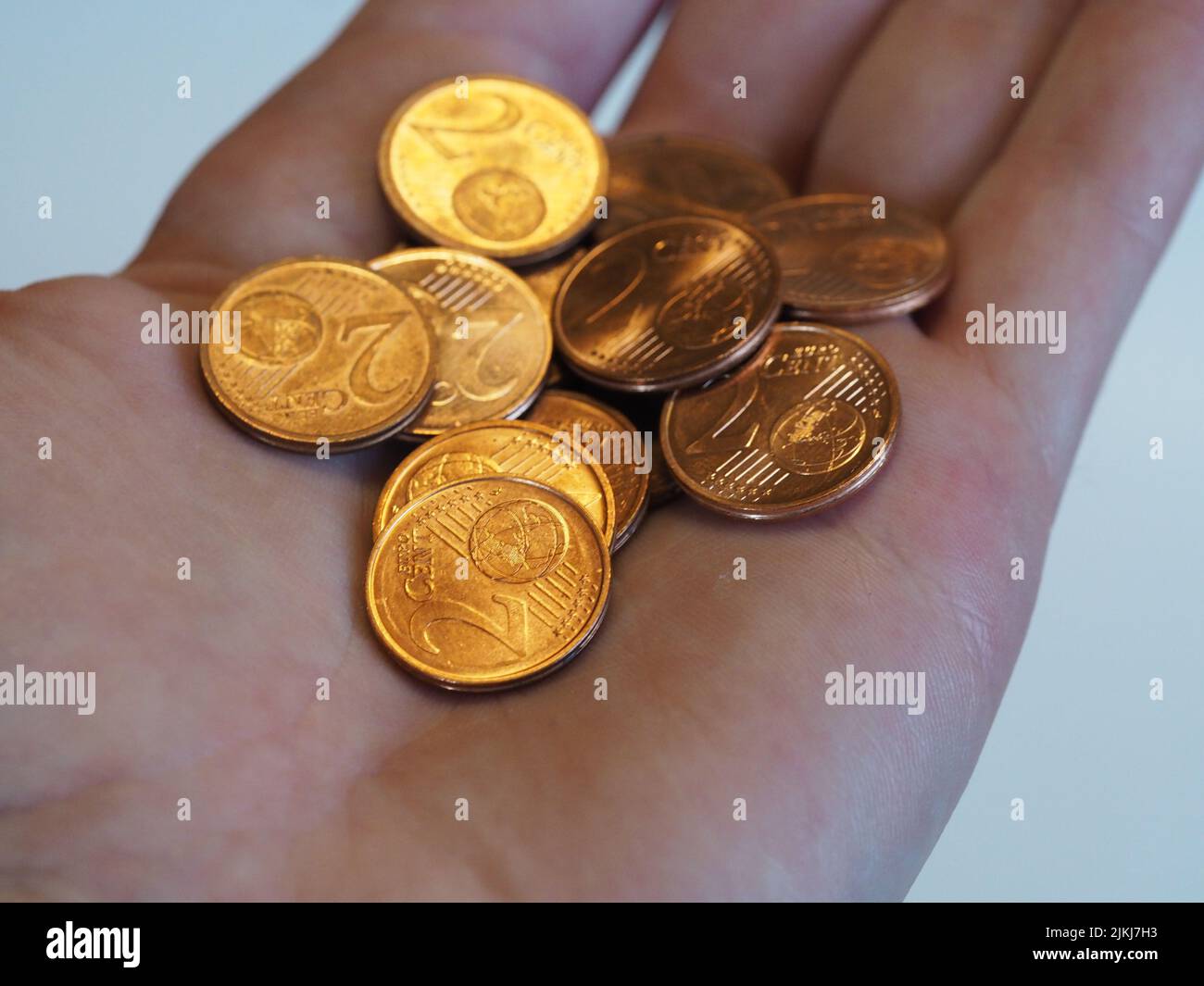 Hand hält glänzende 2-Cent-Münzen mit weißem Bokeh-Hintergrund Stockfoto