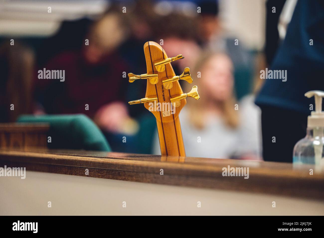 Ein selektiver Fokus einer E-Gitarre, die sich vor einem verschwommenen Hintergrund an einer Wand lehnt Stockfoto