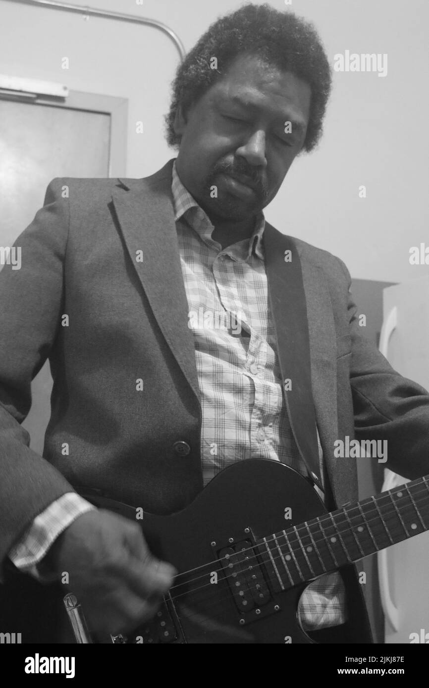 Eine Graustufenaufnahme eines schwarzen Mannes, der Gitarre spielt Stockfoto