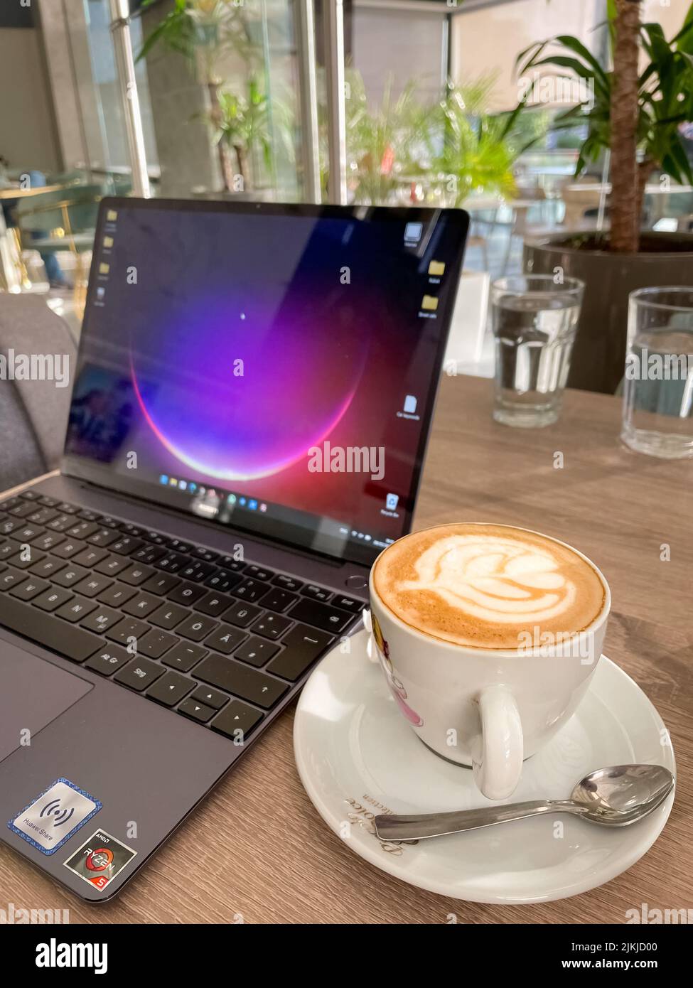 Huawei Matebook 13 Laptop neben einem Latte-Kaffee in einem Café Stockfoto