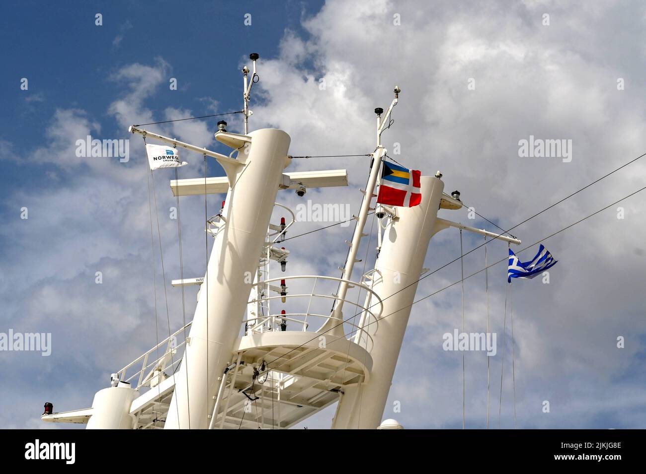 Athen, Griechenland - Mai 2022: Die Flaggen Griechenlands und des Kreuzfahrtbetreibers Norwegian Cruise Line fliegen vom Mast aus auf einem Schiff Stockfoto