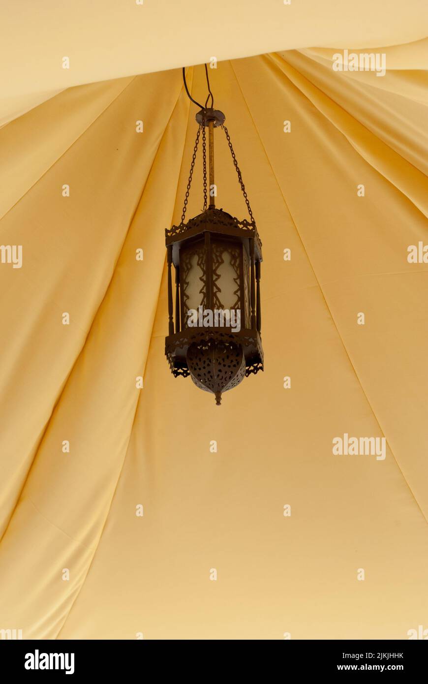 Eine braun verzierte Vintage-Laterne, die in einem gelben Zelt hängt Stockfoto