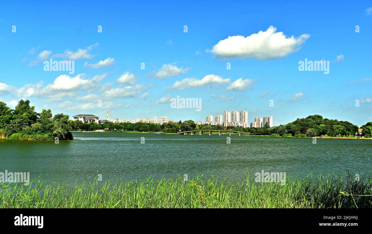 Eine schöne Aufnahme eines Sees mit einem hohen Gebäude und dem Himmel im Hintergrund. China, Blick durch den Jinshan Lake Park. Stockfoto
