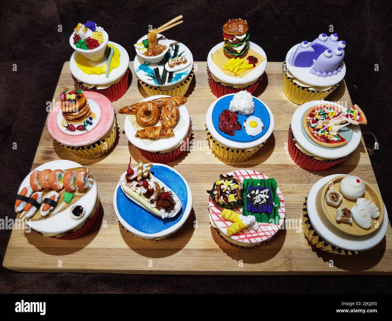Eine Nahaufnahme von kunstvollen Cupcakes mit Miniatur-Food-Toppers auf einem Holzbrett Stockfoto