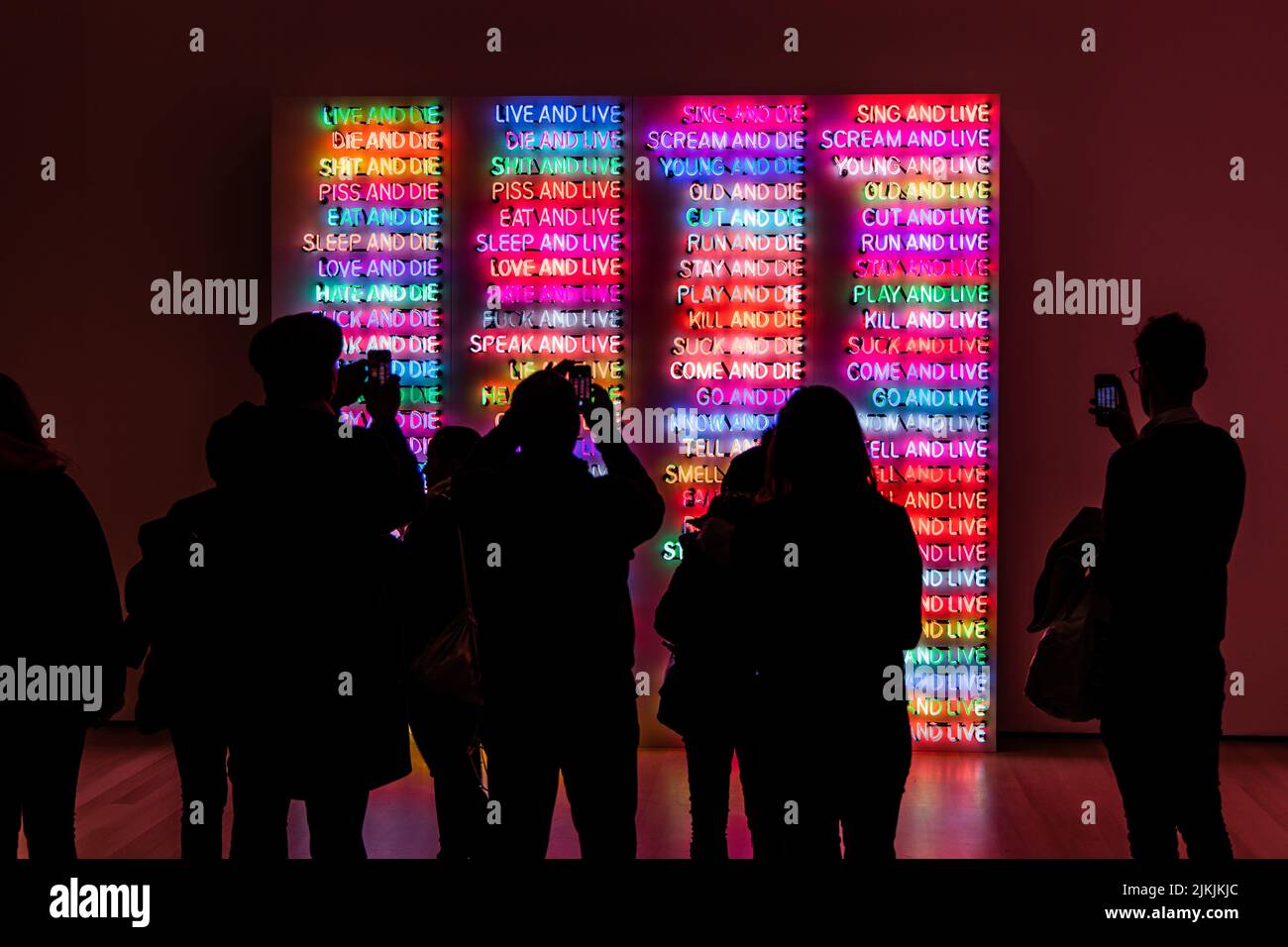 Eine Rückansicht von Menschen, die in einem Museum in New York Fotos von beleuchteten Neonschildern machen Stockfoto