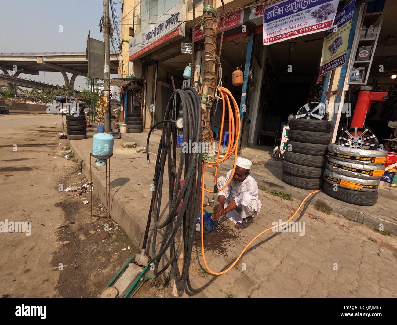 Eine schöne Aufnahme eines traditionellen Mannes, der in einer Autoreifenwerkstatt in Dhaka City, Bangladesch, arbeitet Stockfoto