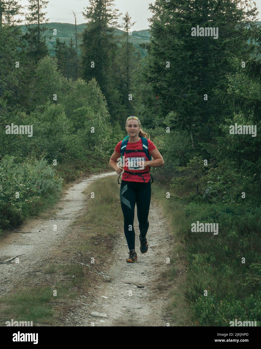 Eine vertikale Aufnahme einer jungen kaukasischen Frau, die einen Marathon auf einem Waldweg läuft Stockfoto