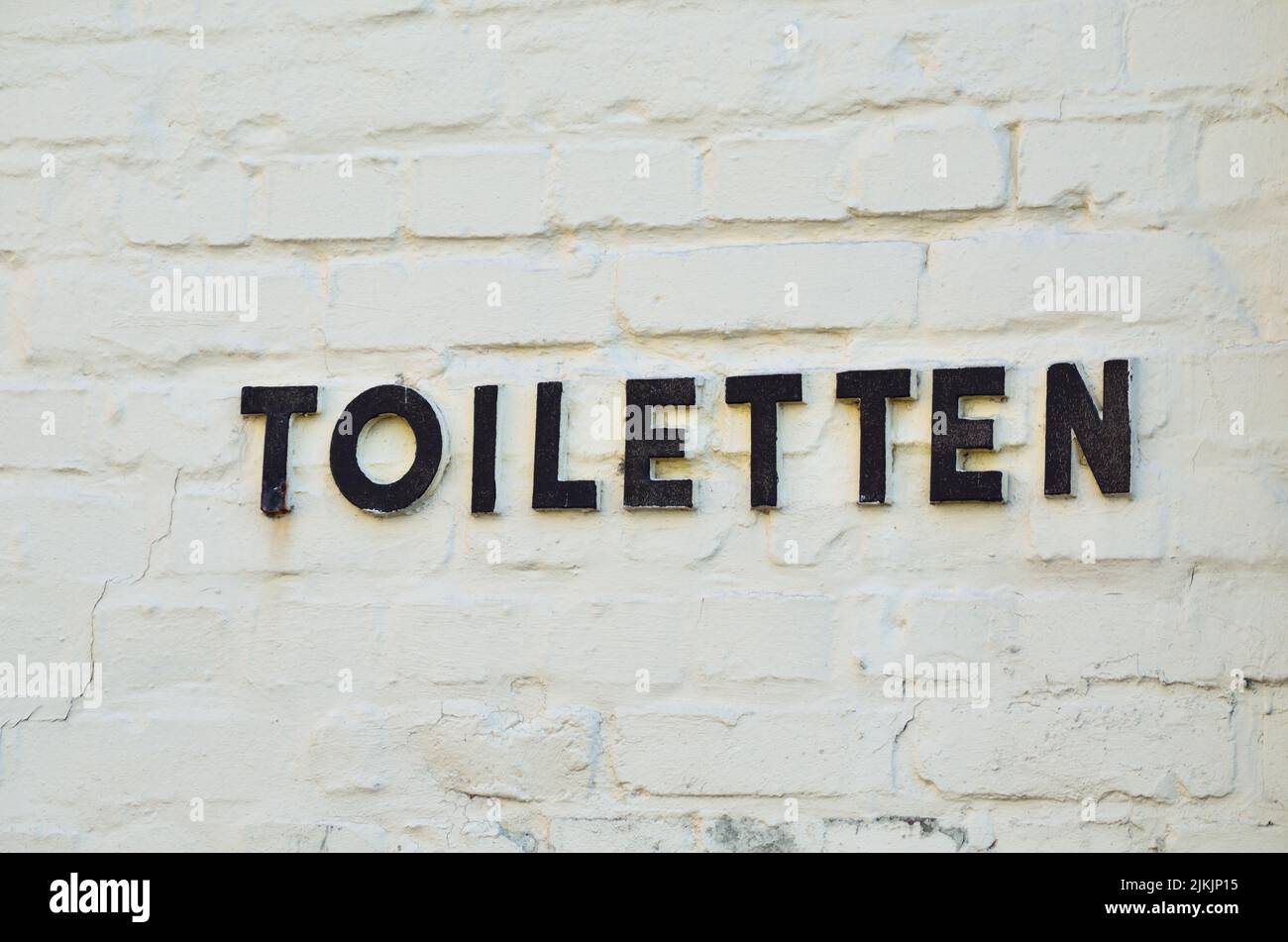 Briefe aus Metall zeigen auf eine Toilette. Stockfoto