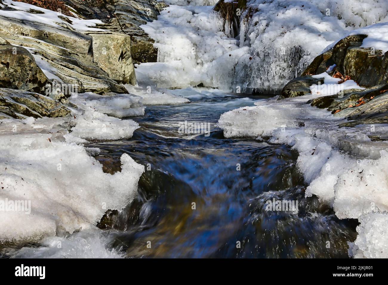 Eine Nahaufnahme von Wasser, das durch Schnee und Eis, Felsen fließt Stockfoto
