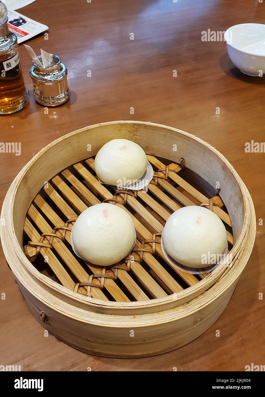 Eine vertikale Nahaufnahme von Dim Sum mit Lotus-Samenbrötchen in einem traditionellen Dampfkorb. Hongkong. Stockfoto