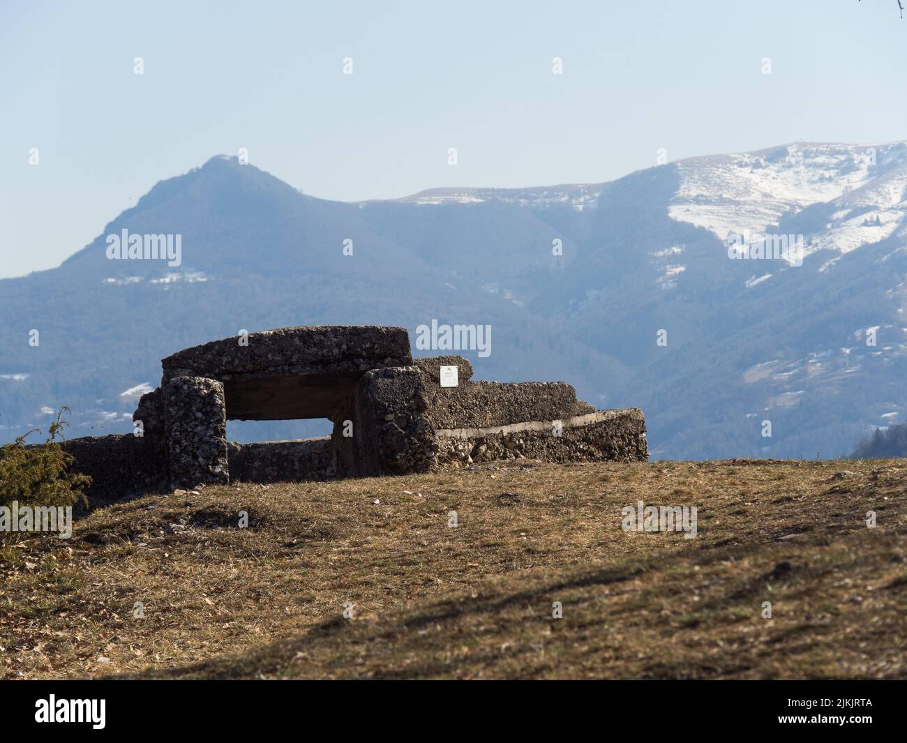 Schöne Aufnahme eines Baumes und eines alten Steinsitzes und Schneeberge mit blauem Himmel am Horizont Stockfoto