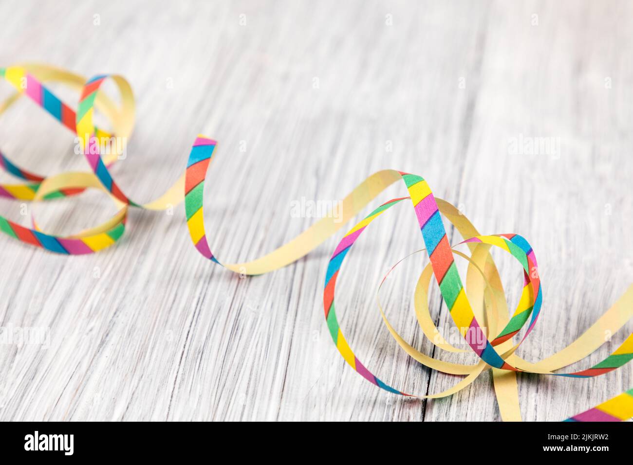 Eine Nahaufnahme von bunten Luftschlangen für Party- oder Karnevalsdekorationen auf einer Holzfläche Stockfoto