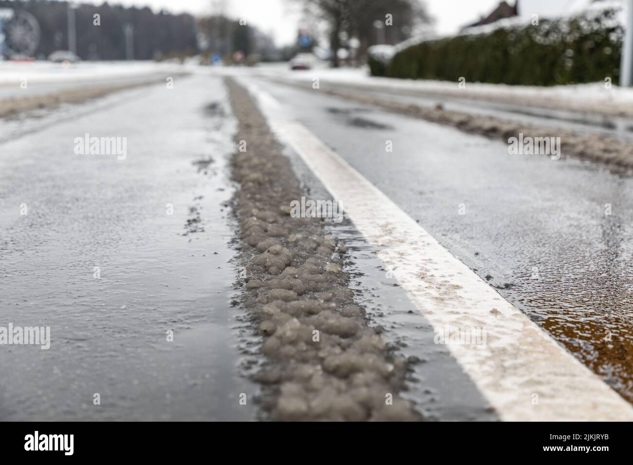 Der geschmolzene Schnee auf der Straße mit Straßenlinien Stockfoto