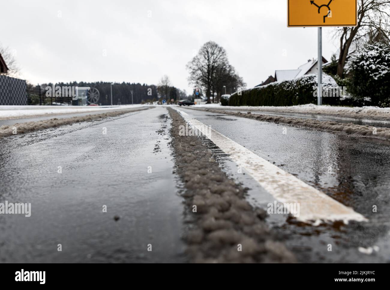 Der geschmolzene Schnee auf der Straße mit Straßenlinien Stockfoto