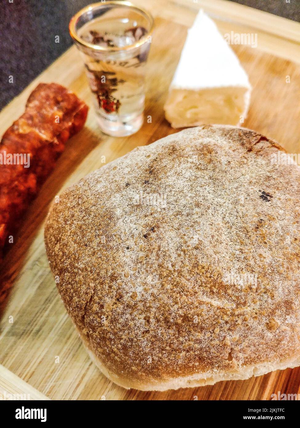 Eine Nahaufnahme eines frisch gebackenen Brotes, ein Glas Wodka, ein Stück Käse und Salami Stockfoto