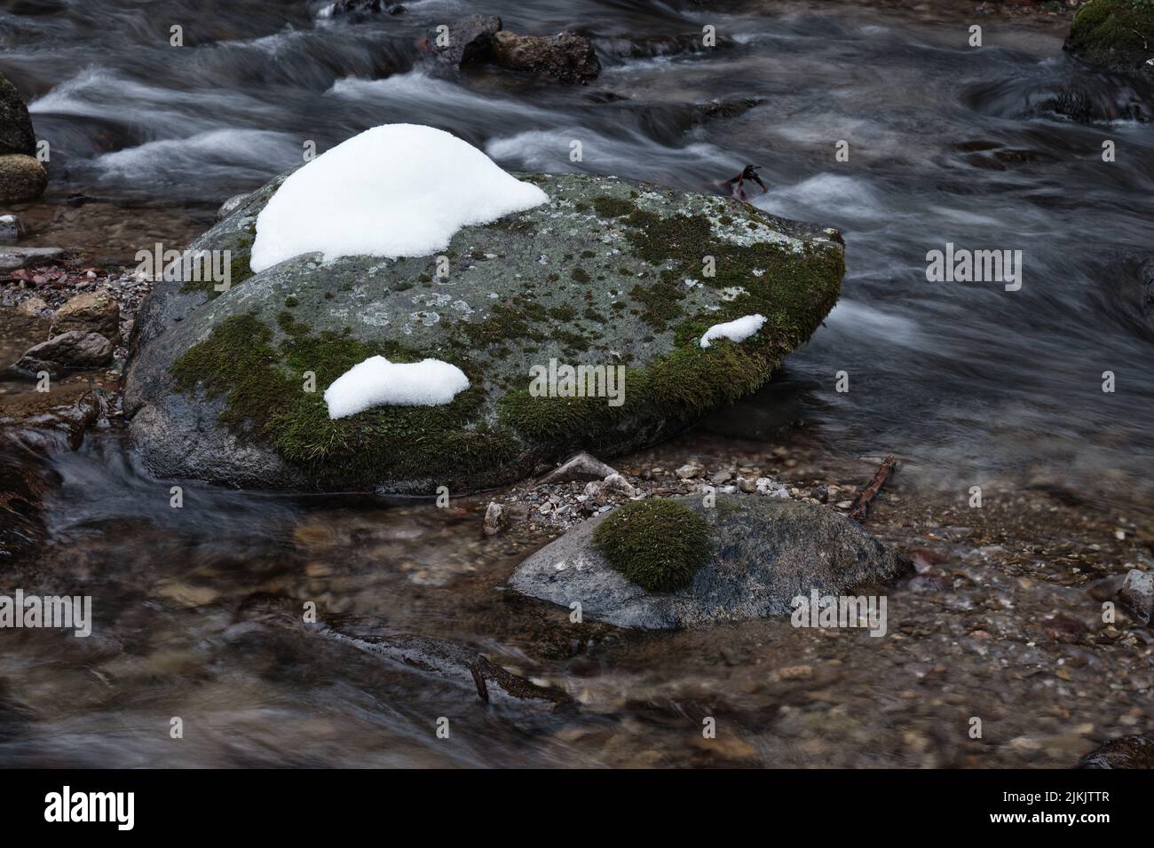 Ein wunderschöner Fluss eines Gebirgsflusses mit schnell fließendem Wasser, Felsen und Schnee Stockfoto