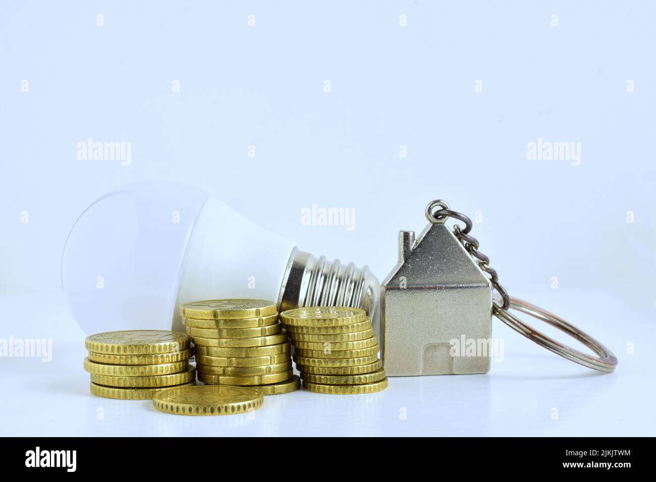 Die goldenen Euro-Münzen neben einem Haustrinket und Glühbirne - Home Economic Concept Stockfoto