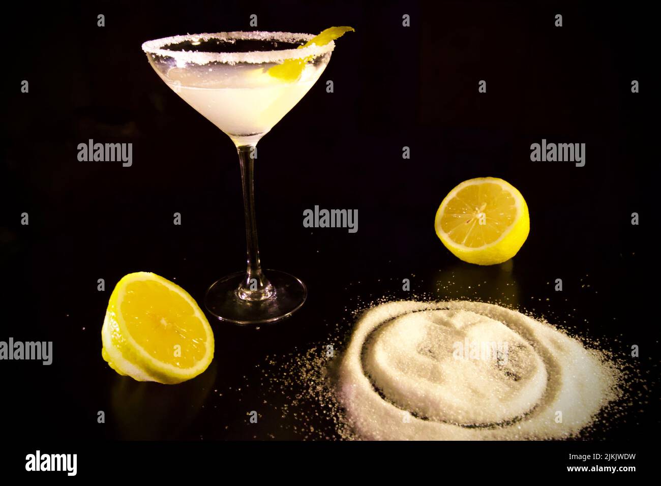 Eine Nahaufnahme von Lemon Drop martini Cocktail und Teig mit Mehl isoliert mit schwarzem Hintergrund Stockfoto