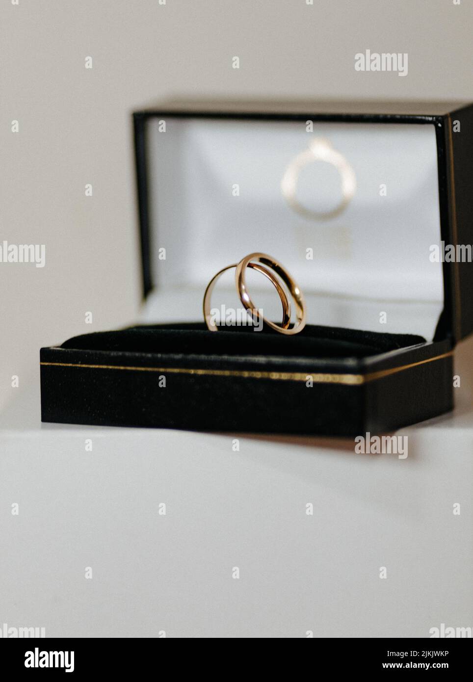 Eine vertikale Nahaufnahme von zwei Eheringen in einer schwarzen Geschenkbox vor grauem Hintergrund Stockfoto