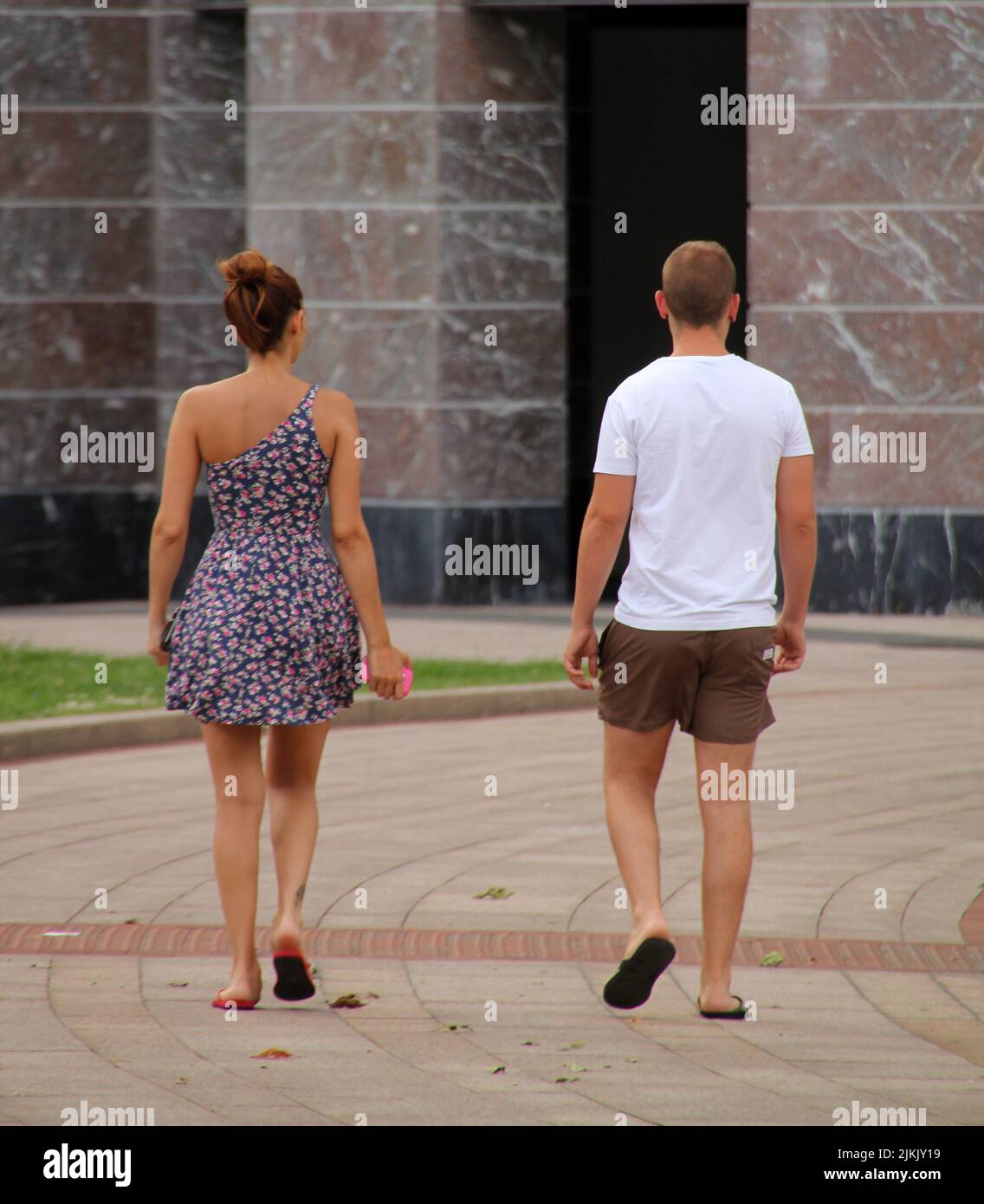 Eine Rückansicht eines Paares im Sommer-Outfit, das im Sommer im Park spazierengeht Stockfoto
