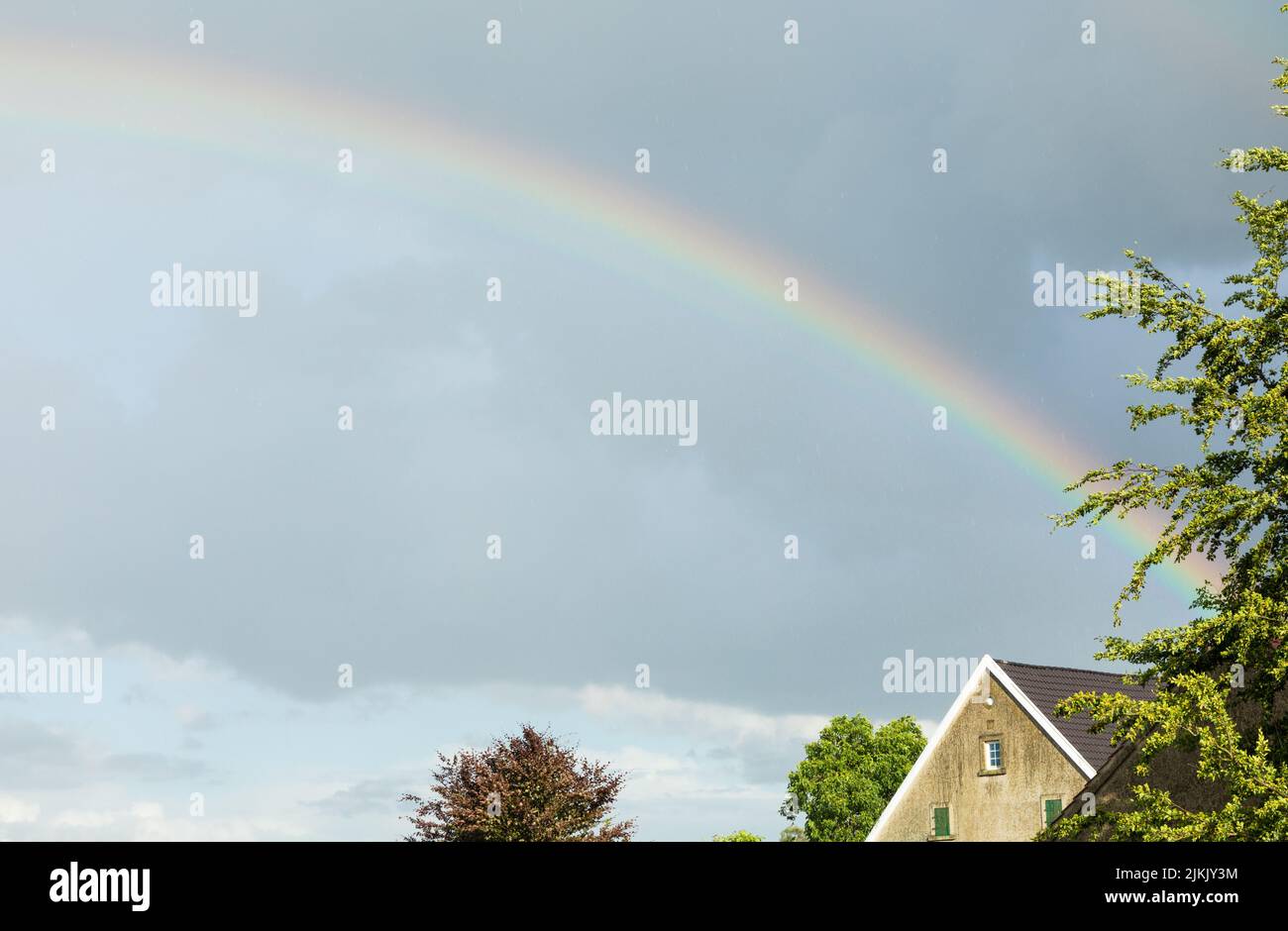 Farbenfroher Regenbogen am Himmel mit Haus Stockfoto