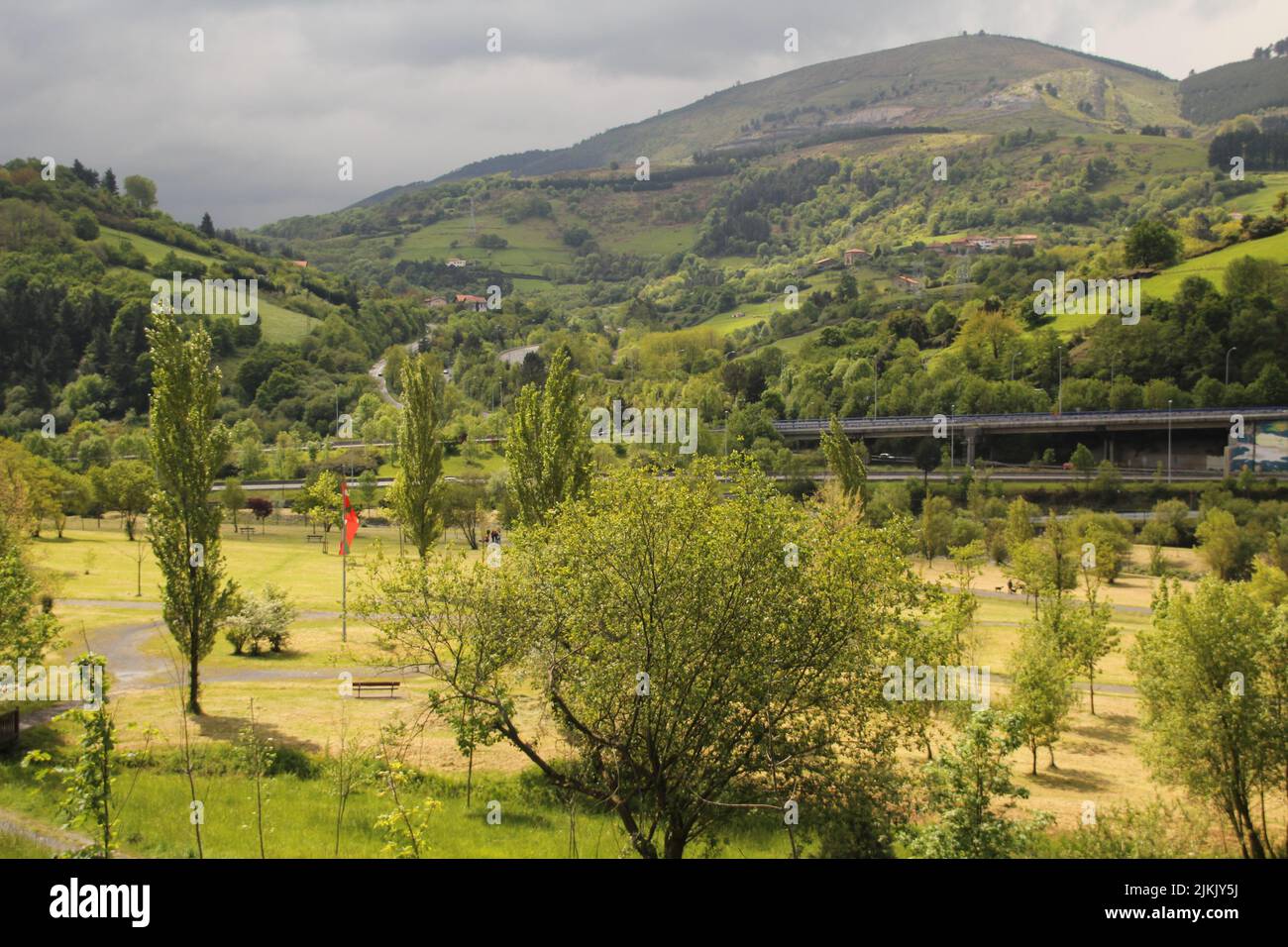 Eine malerische Aussicht auf einen Park und Autobahnen gegen grüne Berge an einem bewölkten Tag Stockfoto