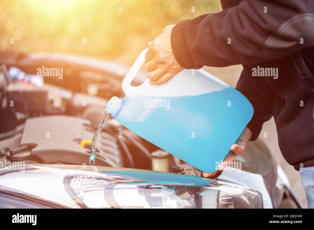 Mann füllt Scheibenwischerwasser auf einem Auto Stockfoto