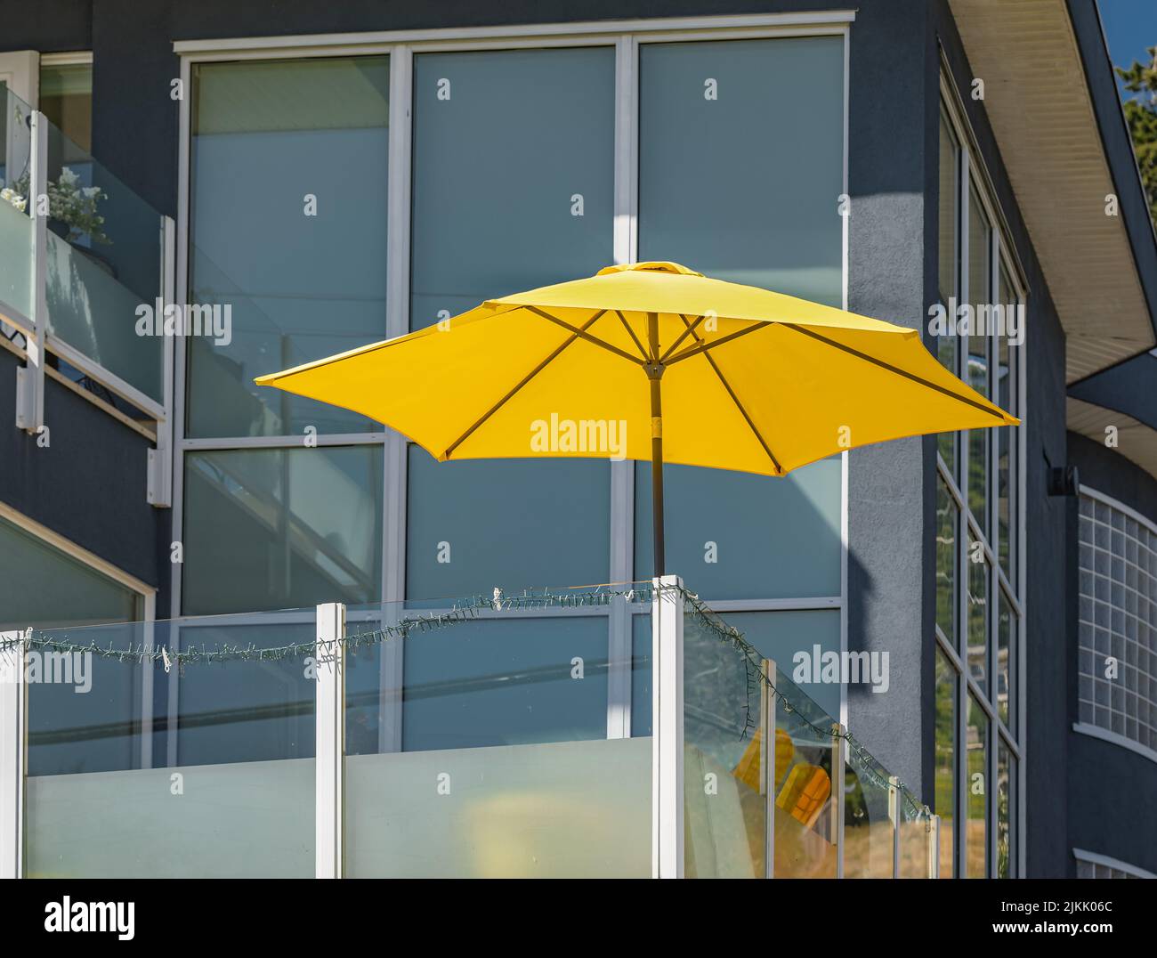 Gelber Sonnenschirm auf dem Balkon bei heißem Sommertag brennend. Reisefoto, Blick auf die Straße, niemand Stockfoto