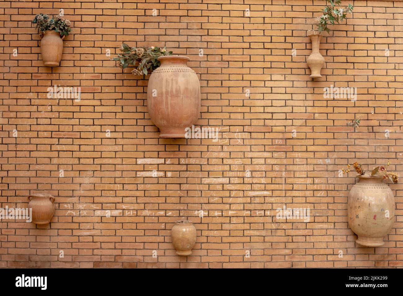 Eine braune Ziegelwand mit Lehmblumentöpfen Stockfoto