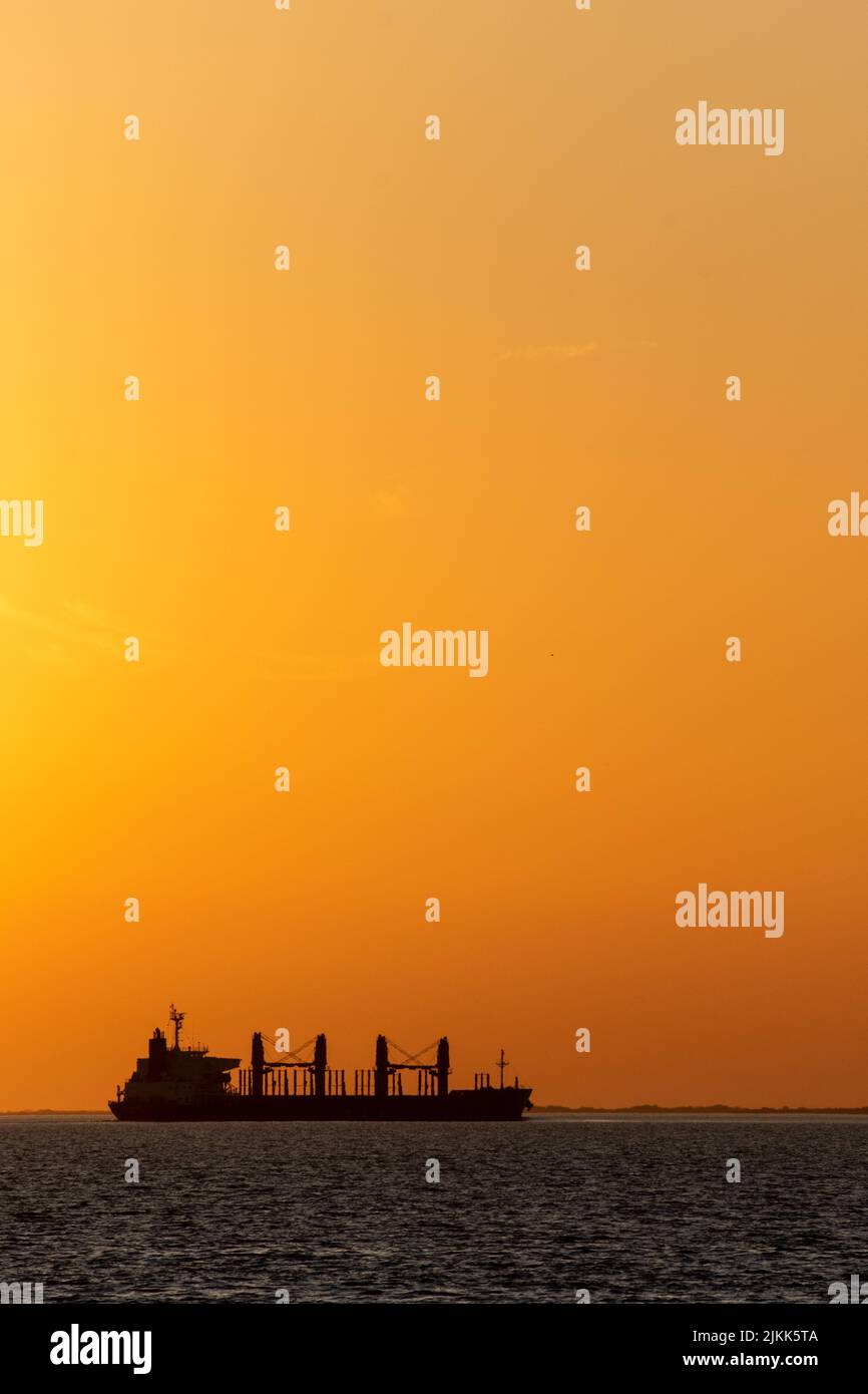 Ein großes Frachtschiff, ein kleines Boot und eine alte Anlegestelle sind am Uruguay River, Conchillas, Uruguay zu sehen Stockfoto