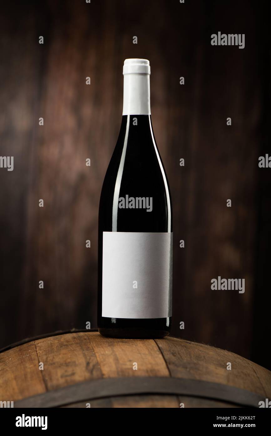 Eine Rotweinflasche auf Woddenfass mit einem hölzernen Backgorund aus der Nähe Stockfoto