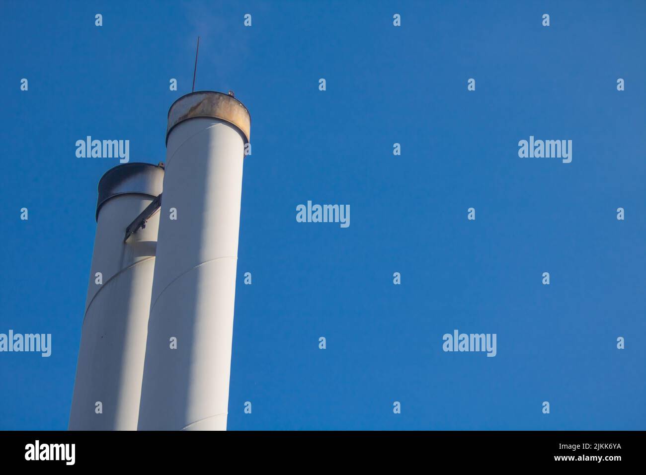 Kamine eines Holzpellet-Kraftwerks für die lokale Wärmeversorgung vor blauem Himmel Stockfoto