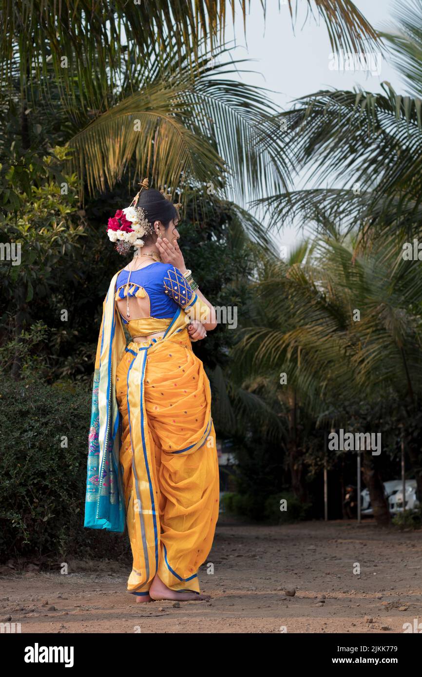 Eine vertikale Aufnahme einer Frau in einem traditionellen Sari in einem tropischen Park Stockfoto