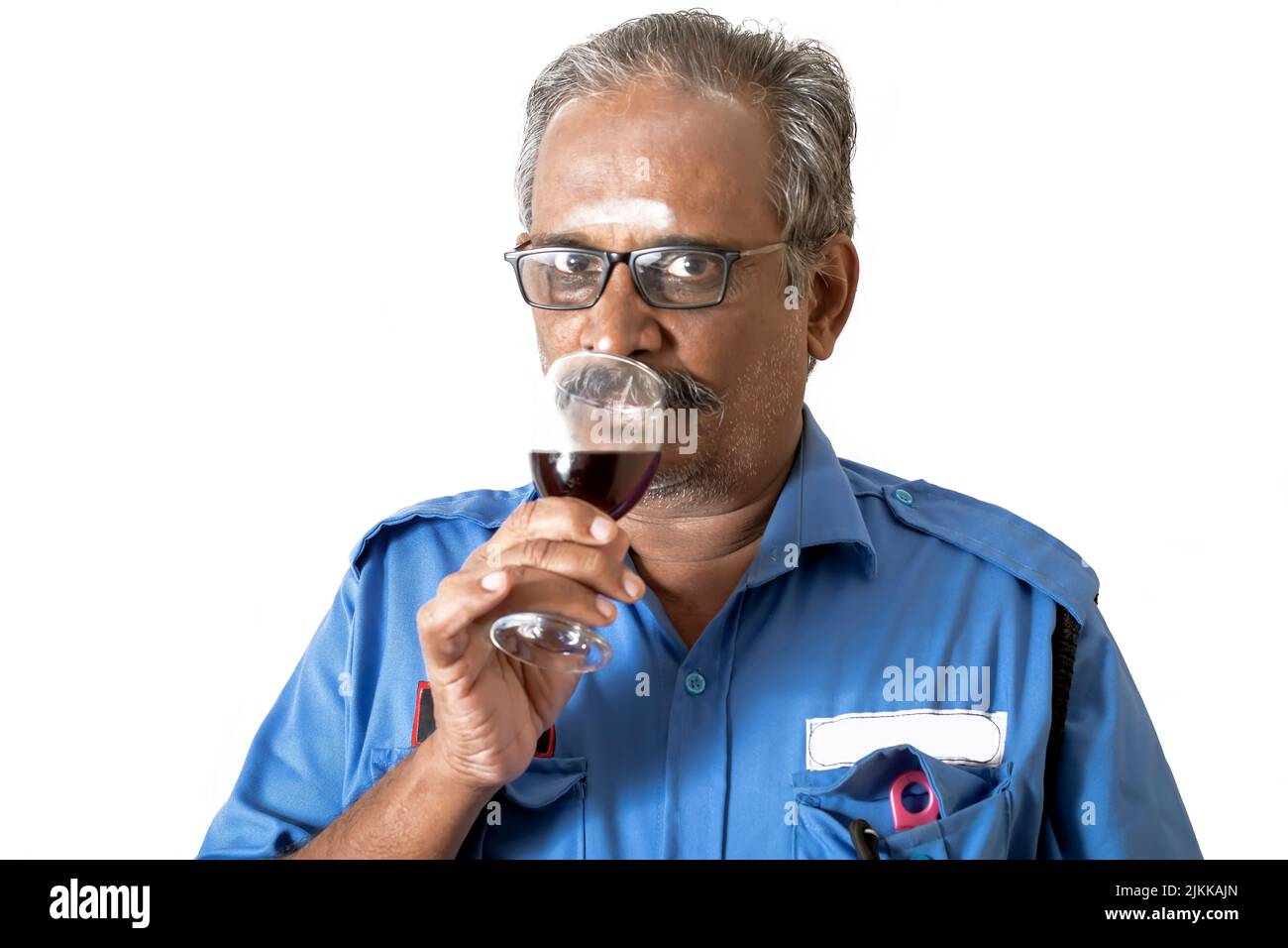 Ein indischer Mann in blauem Hemd, der Wein auf weißem Hintergrund trinkt Stockfoto