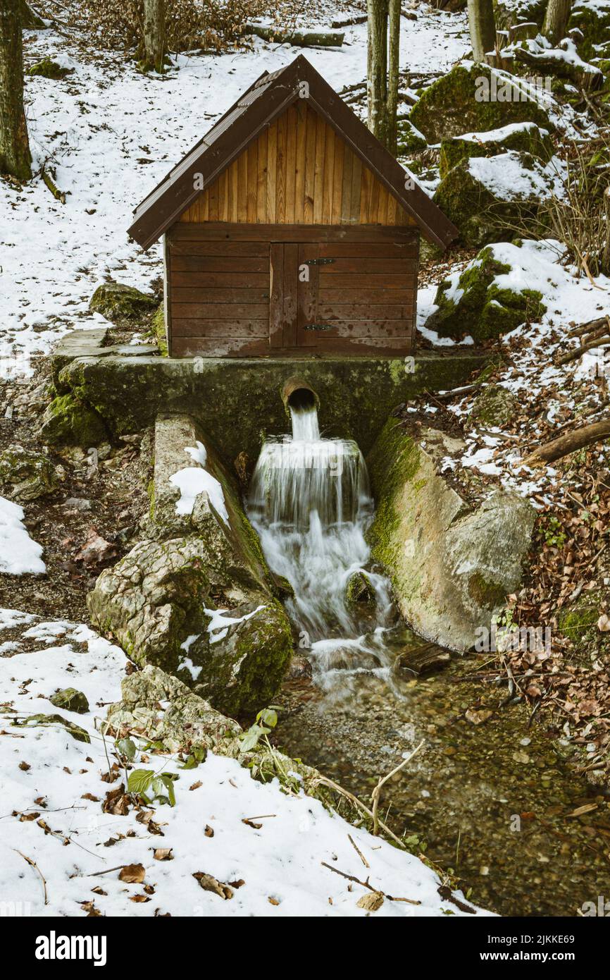 Eine vertikale Wasseraufnahme aus dem Rohr und eine hölzerne, hausartige Struktur darüber Stockfoto