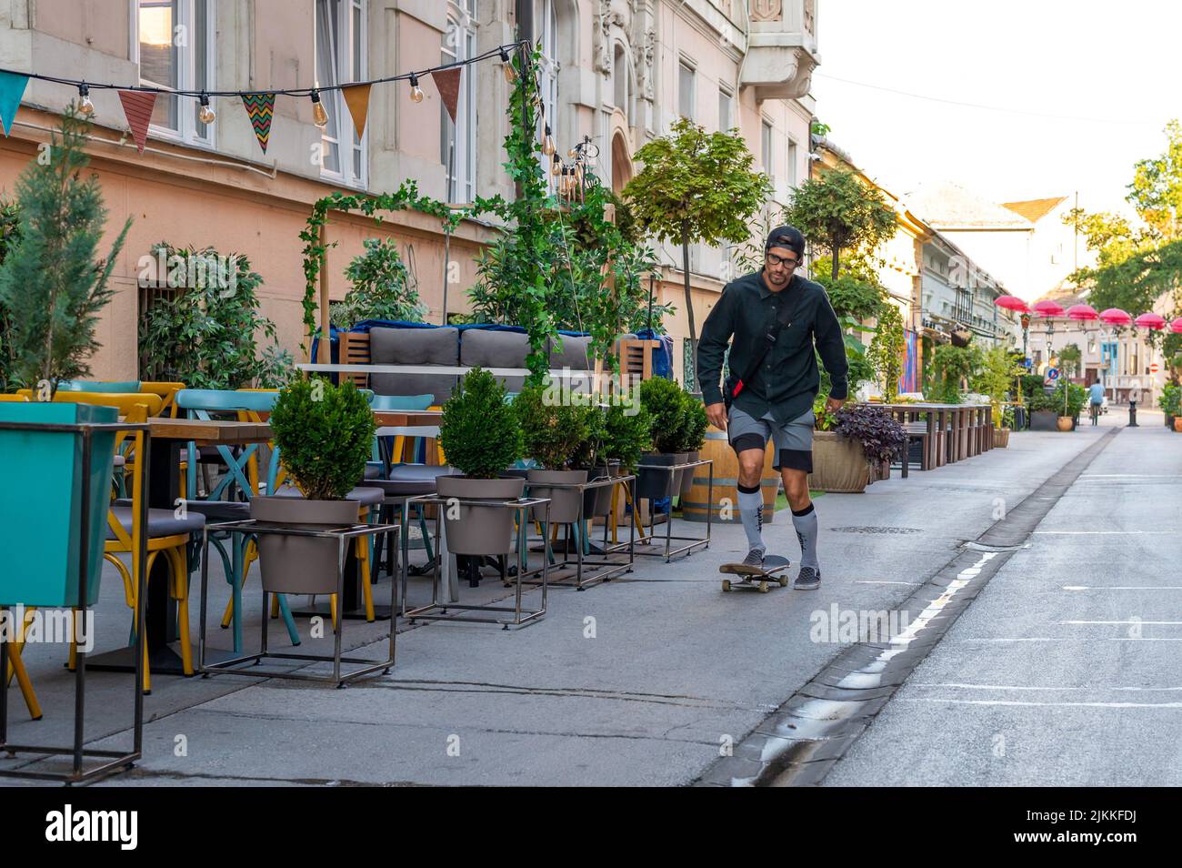 Eine schöne Aufnahme eines erwachsenen kaukasischen Mannes, der an einem sonnigen Tag auf der Straße Skateboarding fährt Stockfoto