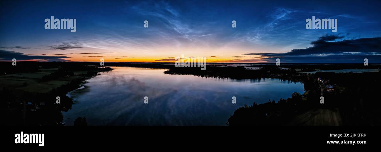 Luftpanorama früher Sonnenaufgang über Nordschweden. Nächtliche Nachtwolken, sommerlicher nebliger See reflektiert den Himmel Stockfoto