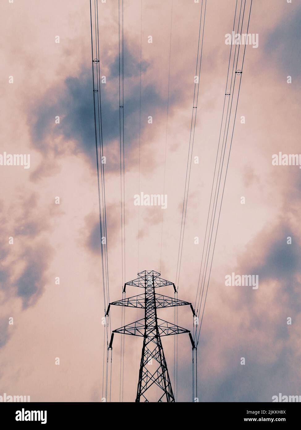 Eine vertikale Aufnahme der Stromübertragungsleitungen im niedrigen Winkel gegen einen bewölkten Himmel Stockfoto