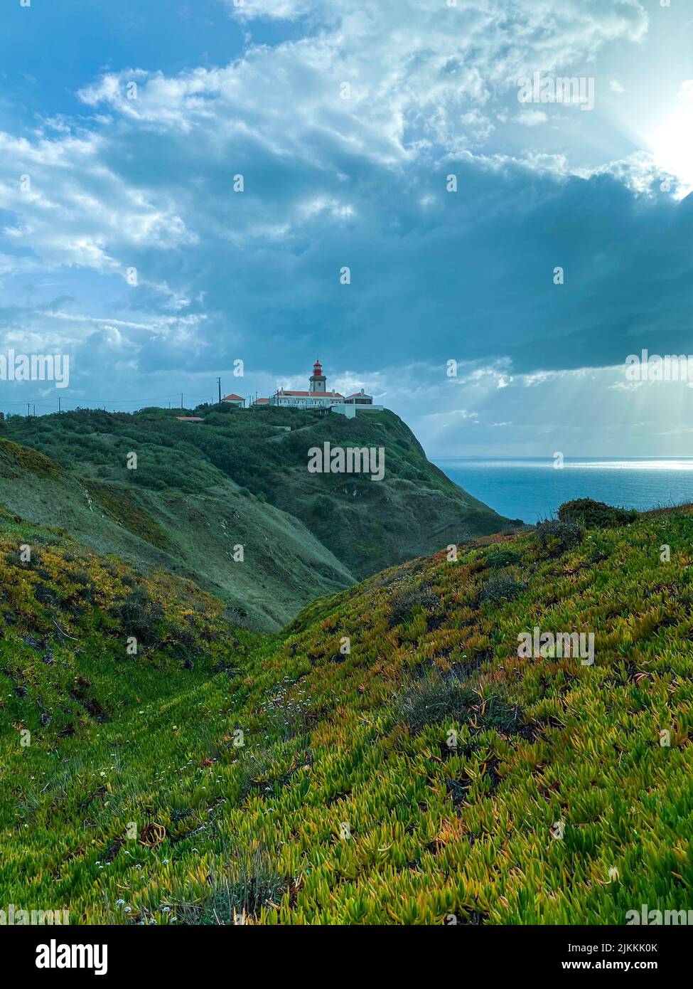 Eine Hügellandschaft mit einem Leuchtturm an einer sonnigen, bewölkten Küste Stockfoto