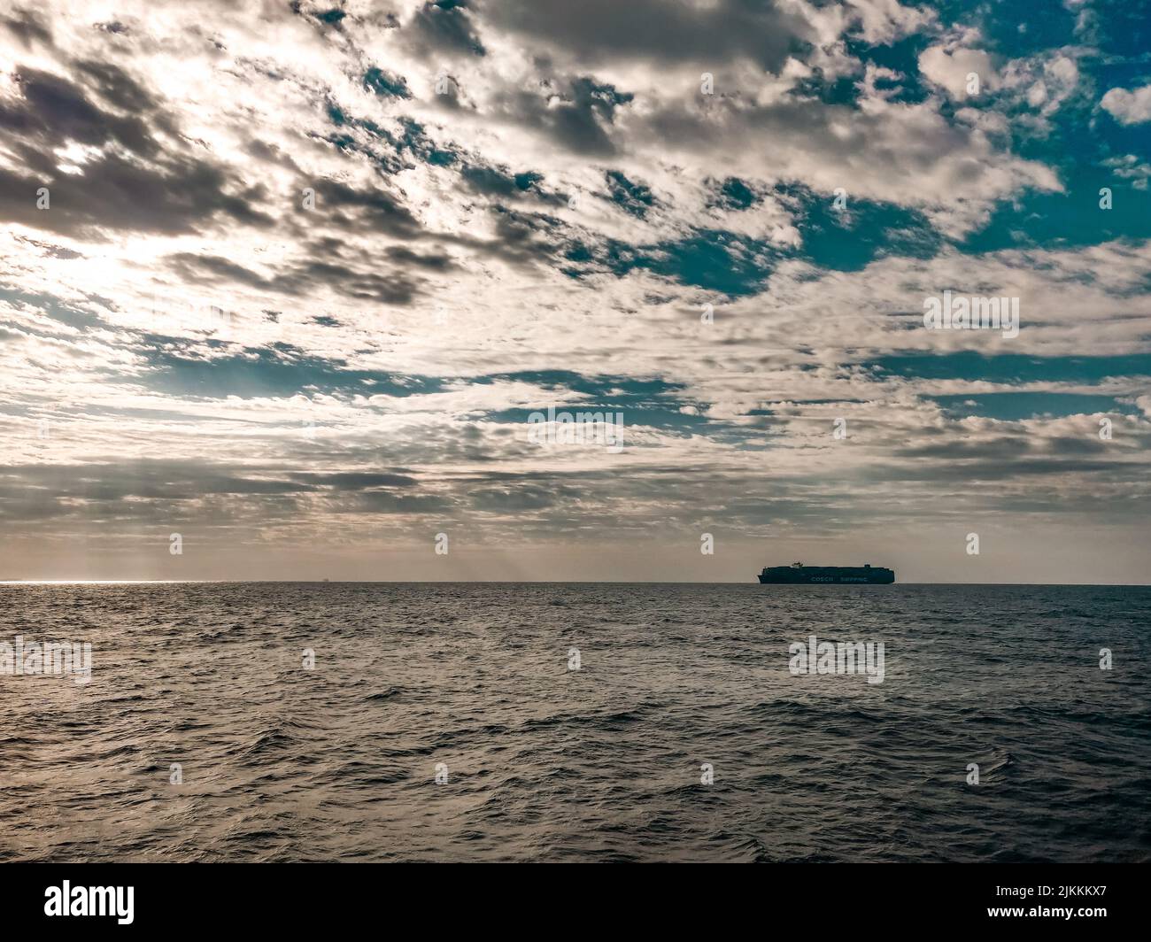 Eine malerische Aussicht auf ein riesiges Schiff, das unter einem blau-bewölkten Himmel auf offenem Meer segelt Stockfoto