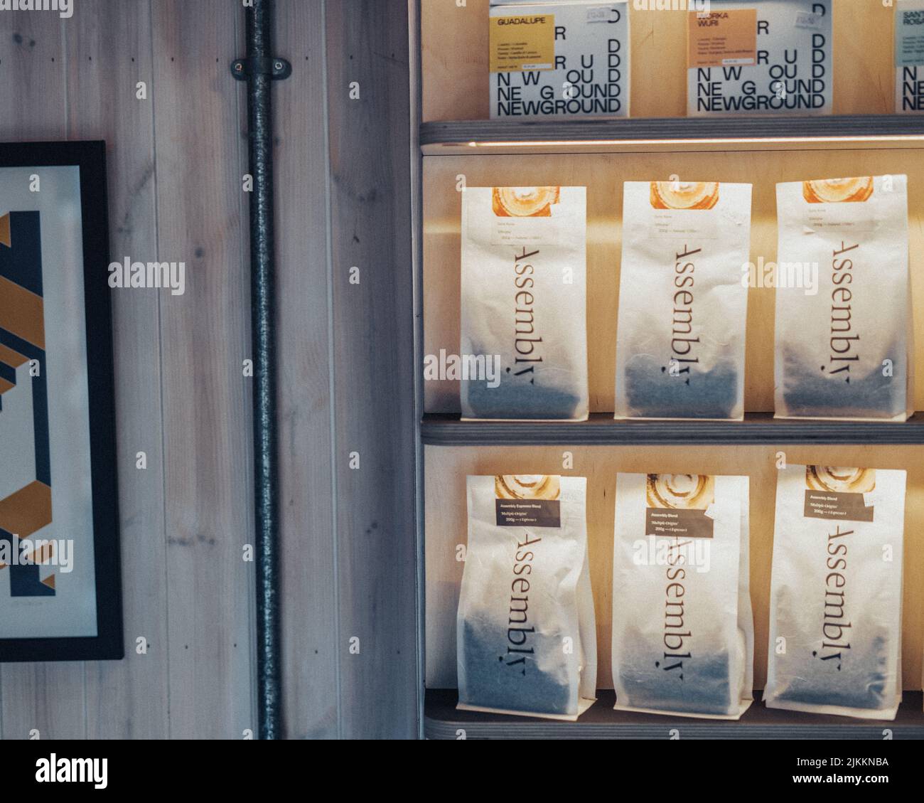 Eine Nahaufnahme von Kaffeetaschen mit Bohnen auf Holzregalen mit warmer Beleuchtung Stockfoto